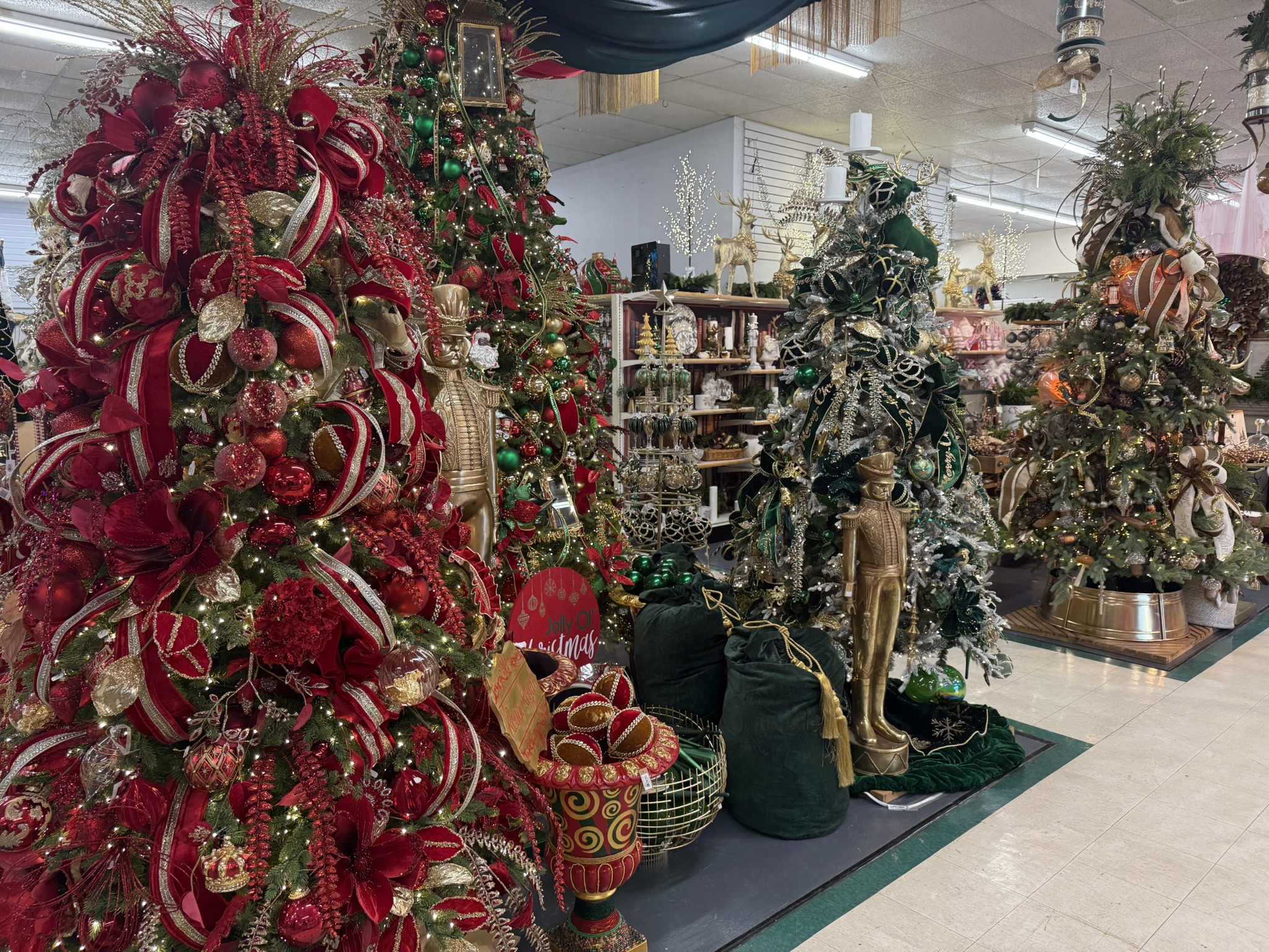 Decorated Christmas trees in a store, featuring red, green, and gold ornaments.