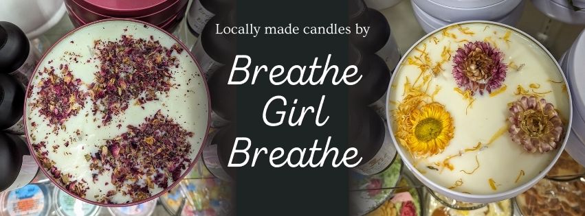 Two decorative candles with dried flowers, labeled "Breathe Girl Breathe."